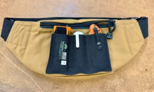 The pocket on the back is secure against the body but may be slow to access while wearing the pack. It is generous enough for most wallets, phones, or flat medical items like chest seals. We recommend choosing relatively thin, flat items for this pocket. Our Basic Pocket Mag Pouch #3 DB fits it perfectly and allows for organization that can be moved between your pant, vest, or jacket pockets and the Defender pack.